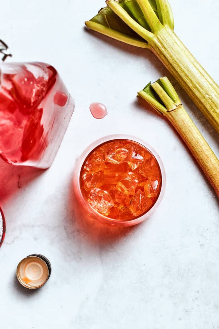 Midwest meets Italy in this summery Rhubarb Aperol Spritz! It’s a light, sparkling and refreshing cocktail perfect for using up fresh rhubarb. Overhead view of rhubarb spritz, rhubarb syrup, and fresh rhubarb