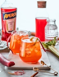 Two glasses of rhubarb aperol spritz with rhubarb shavings for garnish