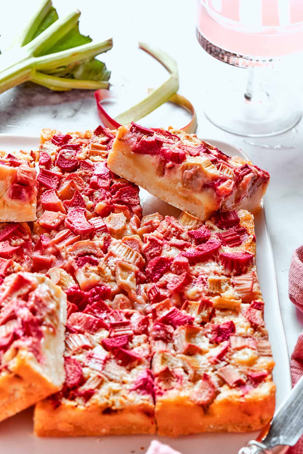 Buttery shortbread is layered with rhubarb custard to create these irresistible Rhubarb Custard Bars. Don't skip the cream cheese topping! rhubarb custard bars on a white platter