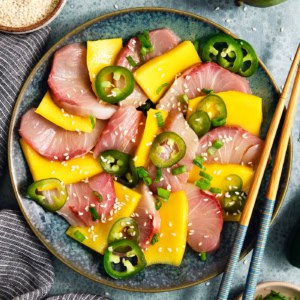 Overhead view of hamachi crudo on plate with mango and pickled jalapeno