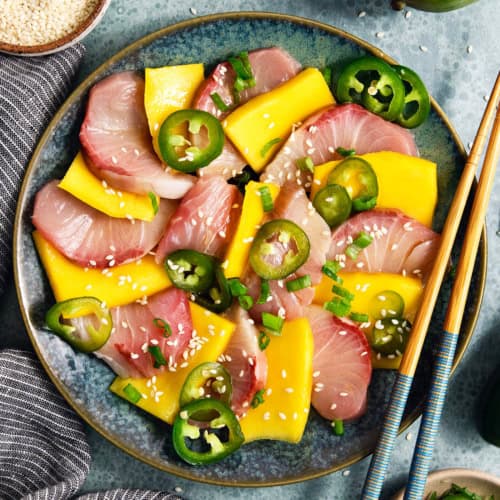 Overhead view of hamachi crudo on plate with mango and pickled jalapeno