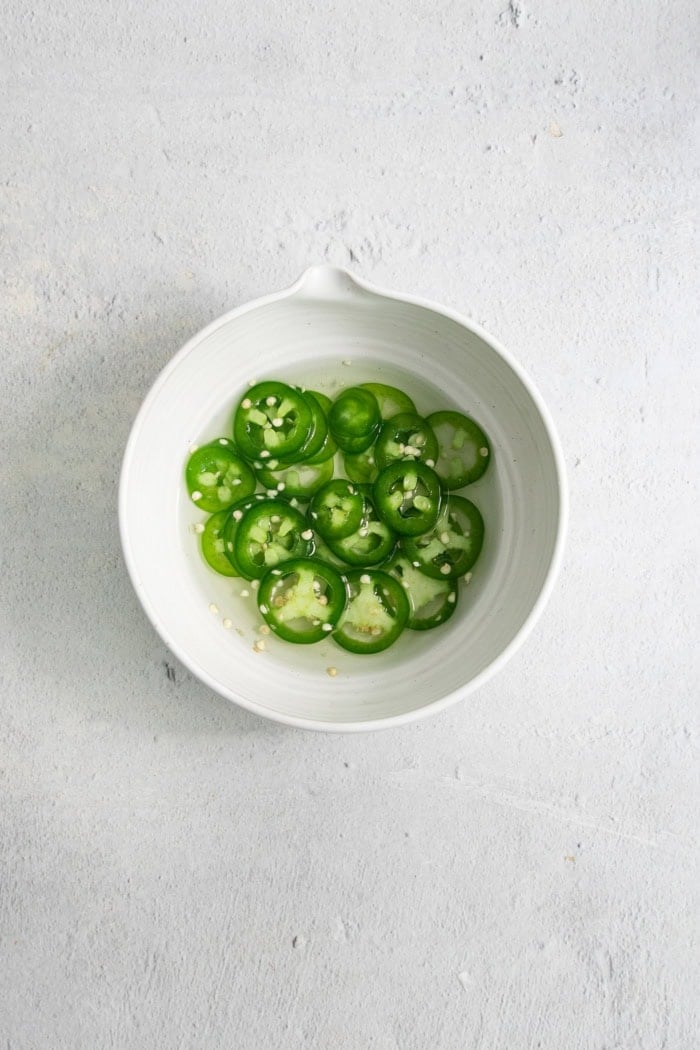 Sweet mangoes and pickled jalapeño peppers make this Hamachi Crudo recipe a standout! It's an easy appetizer that always impresses. Overhead view of pickled jalapenos on small bowl