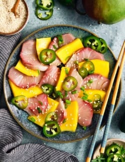 Overhead view of hamachi crudo on plate with mango and pickled jalapenos