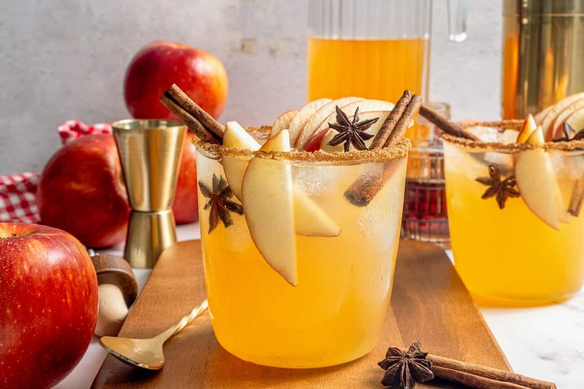 A fall spin on the classic, this Apple Cider Margarita is lightly sweetened with maple syrup and a cinnamon rim add a festive touch! Apple cider margarita in rimmed glass with apple slices, star anise, and cinnamon stick.