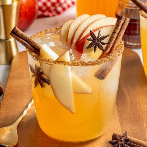 a glass of apple cider margarita with fresh apple slices