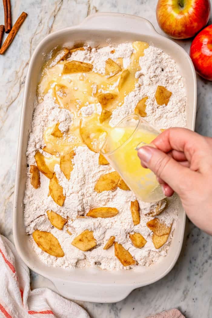 Pouring butter into pan for apple dump cake.