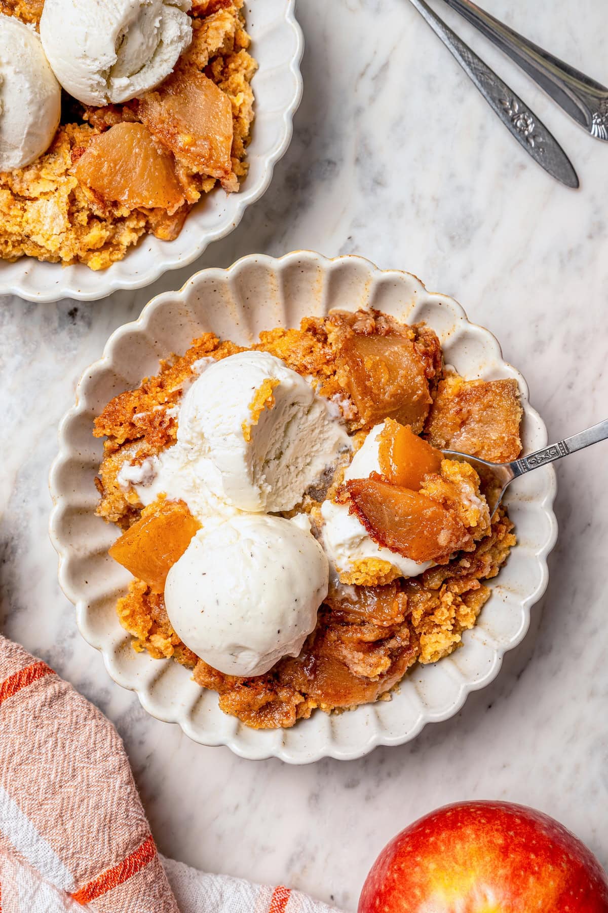 Overhead view of apple dump cake on 2 plates with vanilla ice cream.