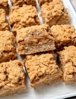Apple pie bars on platter with one on its side to show layers of texture.