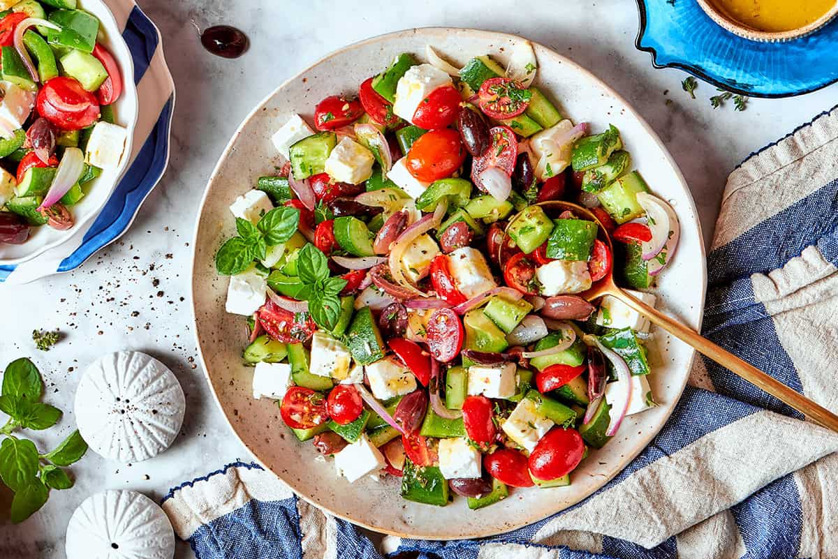 Bright and tangy, with lots of garlic and oregano, this Greek Salad Dressing is easy to make and tastes SO much better than store-bought! chopped Greek salad on a white platter