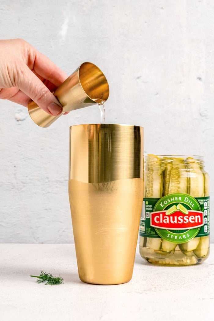 Inspired by the classic dirty martini recipe, pickle brine adds a pop of bold, briny flavor to this savory and smooth pickle martini. Pouring pickle juice into gold cocktail shaker
