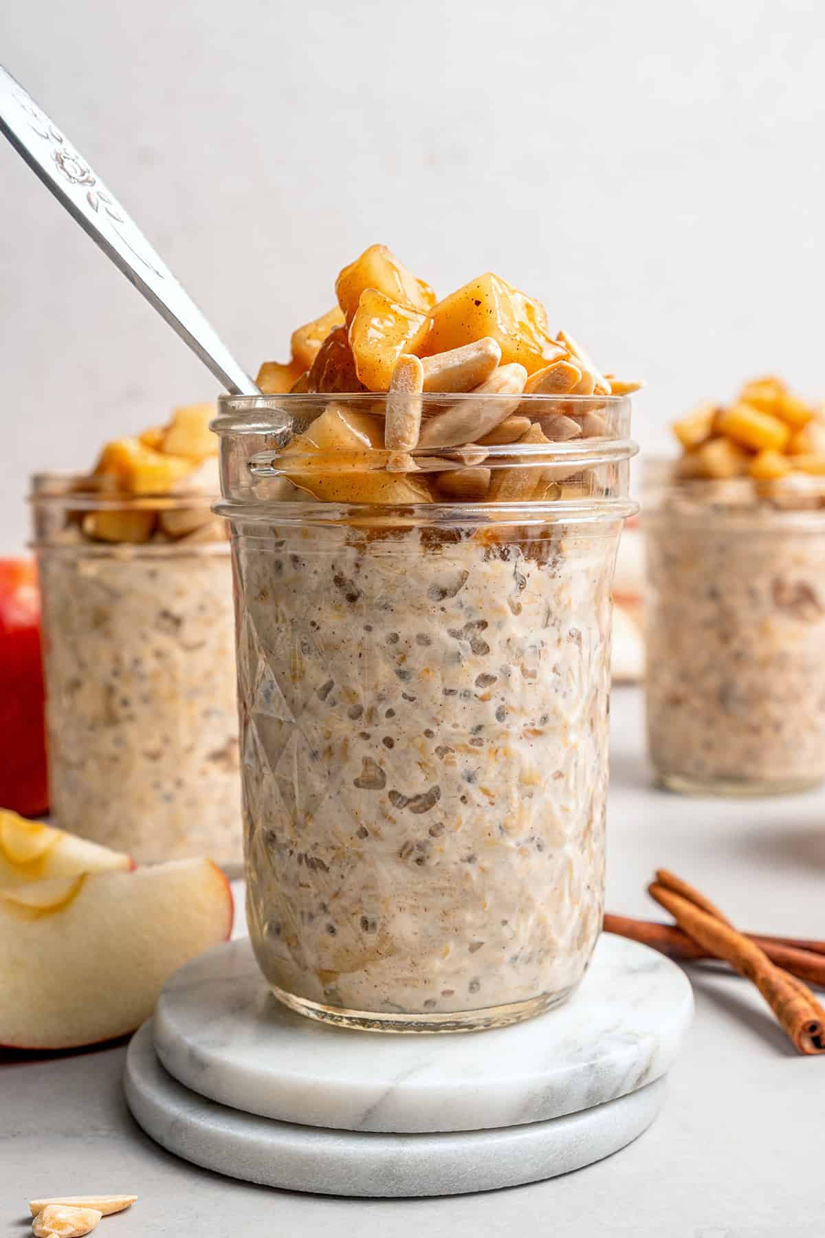 This Apple Cinnamon Overnight Oats recipe is an easy make-ahead breakfast, with the creamiest oats and lots of cozy, tender apples! jars of apple overnight oats with sauteed apples and slivered almonds on top