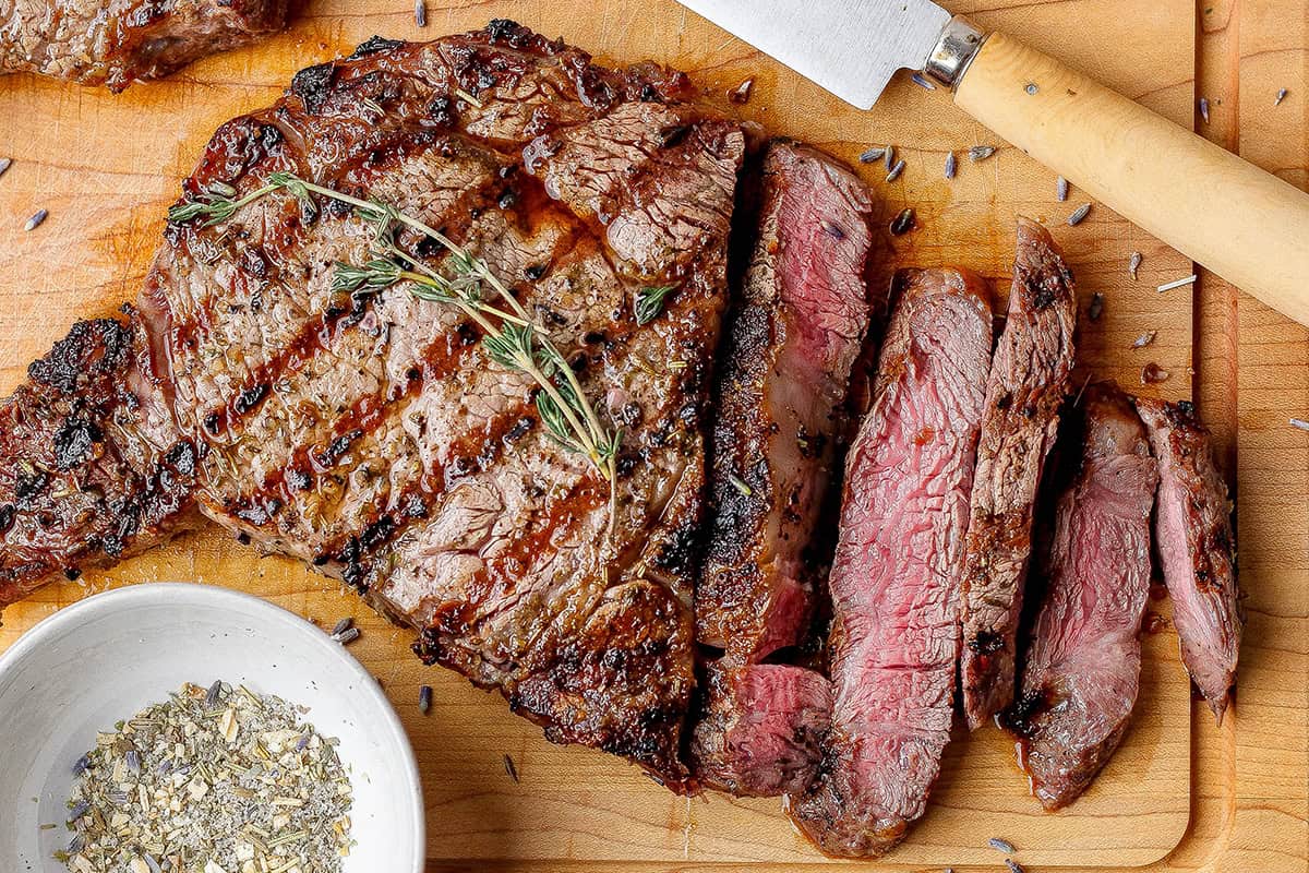 A savory combination of sea salt, toasted onion, black pepper, and herbs make this my family's go-to steak seasoning recipe! Sliced ribeye steak with bowl of steak seasoning.