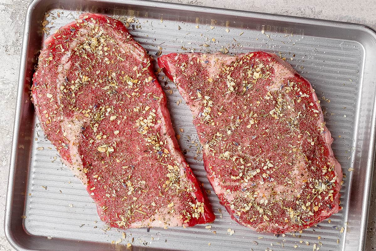 Raw steaks sprinkled with homemade steak seasoning