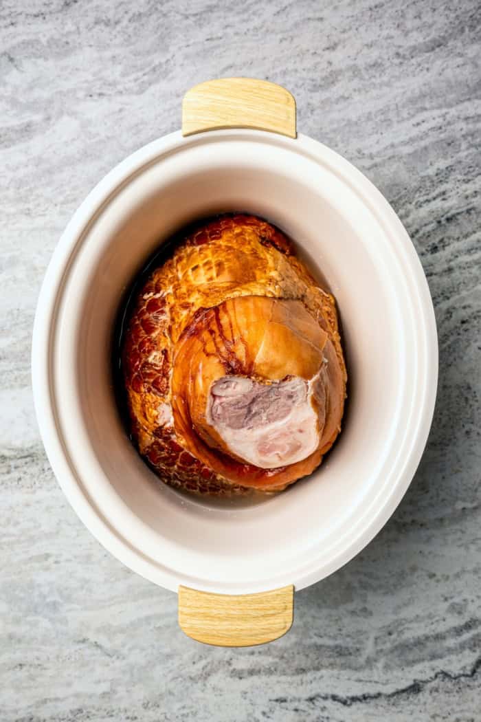 You just need two ingredients for the perfect juicy Crockpot Ham for a crowd! Add the optional glaze and gravy to take it to the next level. Ham set in crockpot.