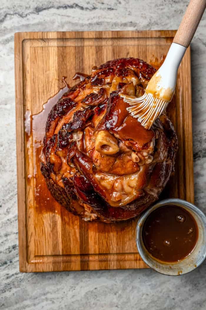 You just need two ingredients for the perfect juicy Crockpot Ham for a crowd! Add the optional glaze and gravy to take it to the next level. Brushing glaze onto cooked ham.
