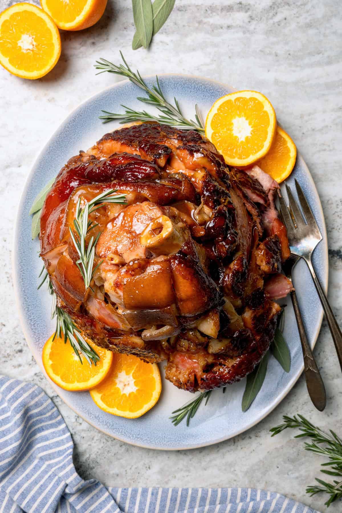 You just need two ingredients for the perfect juicy Crockpot Ham for a crowd! Add the optional glaze and gravy to take it to the next level. Glazed crockpot ham on platter with orange slices and rosemary.