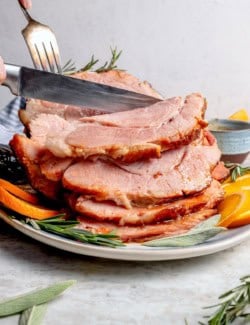 Fork and knife slicing into crockpot ham.