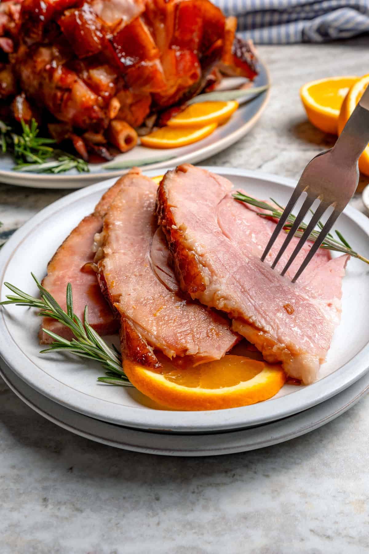 You just need two ingredients for the perfect juicy Crockpot Ham for a crowd! Add the optional glaze and gravy to take it to the next level. Fork piercing slice of crockpot ham on plate.