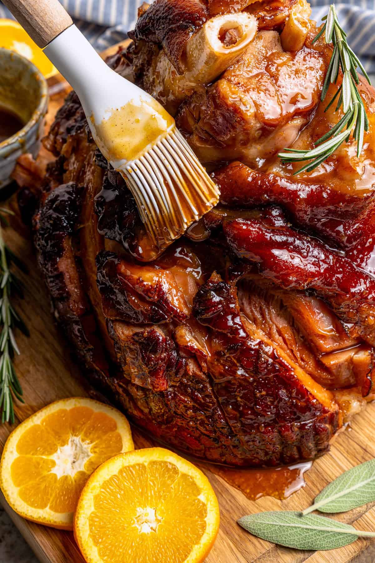 Brushing orange-brown sugar ham glaze onto ham.