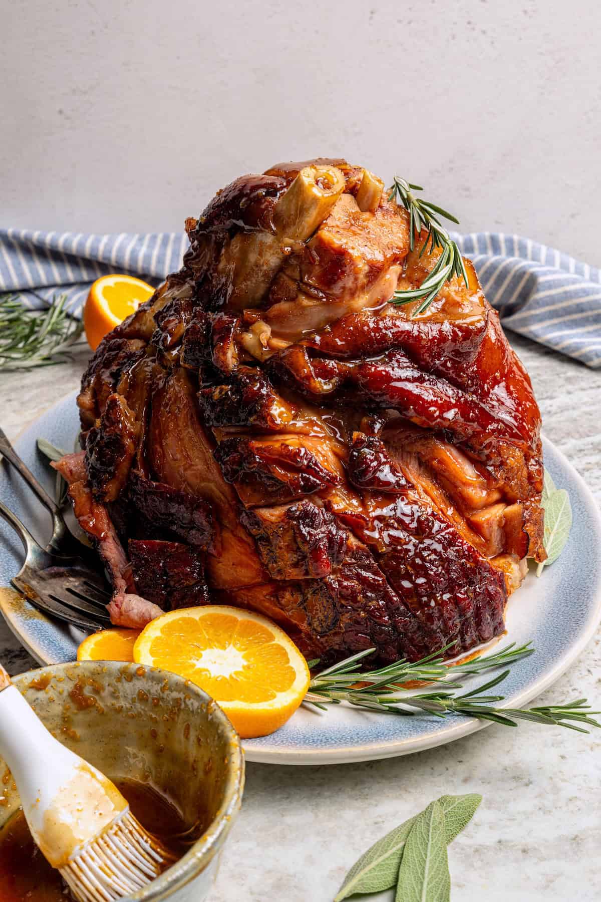 Platter with ham set next to bowl of orange-brown sugar ham glaze.