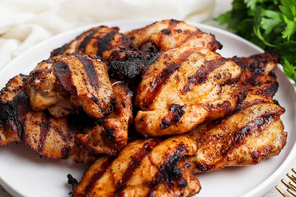 These Grilled Chicken Thighs are tender and juicy, with a smoky char that plays perfectly with the sweet-and-savory seasoning blend. So easy! Platter of grilled chicken thighs.