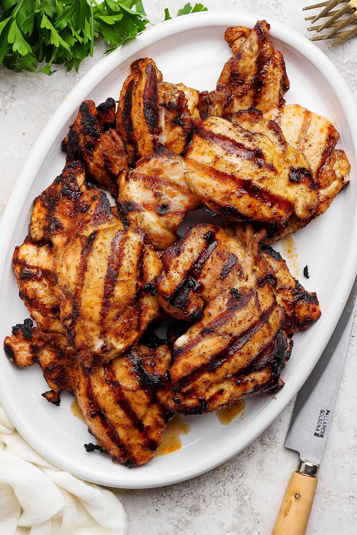 These Grilled Chicken Thighs are tender and juicy, with a smoky char that plays perfectly with the sweet-and-savory seasoning blend. So easy! Platter of grilled chicken thighs.