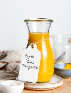 Homemade apple cider vinaigrette in glass bottle with tag tied around neck.