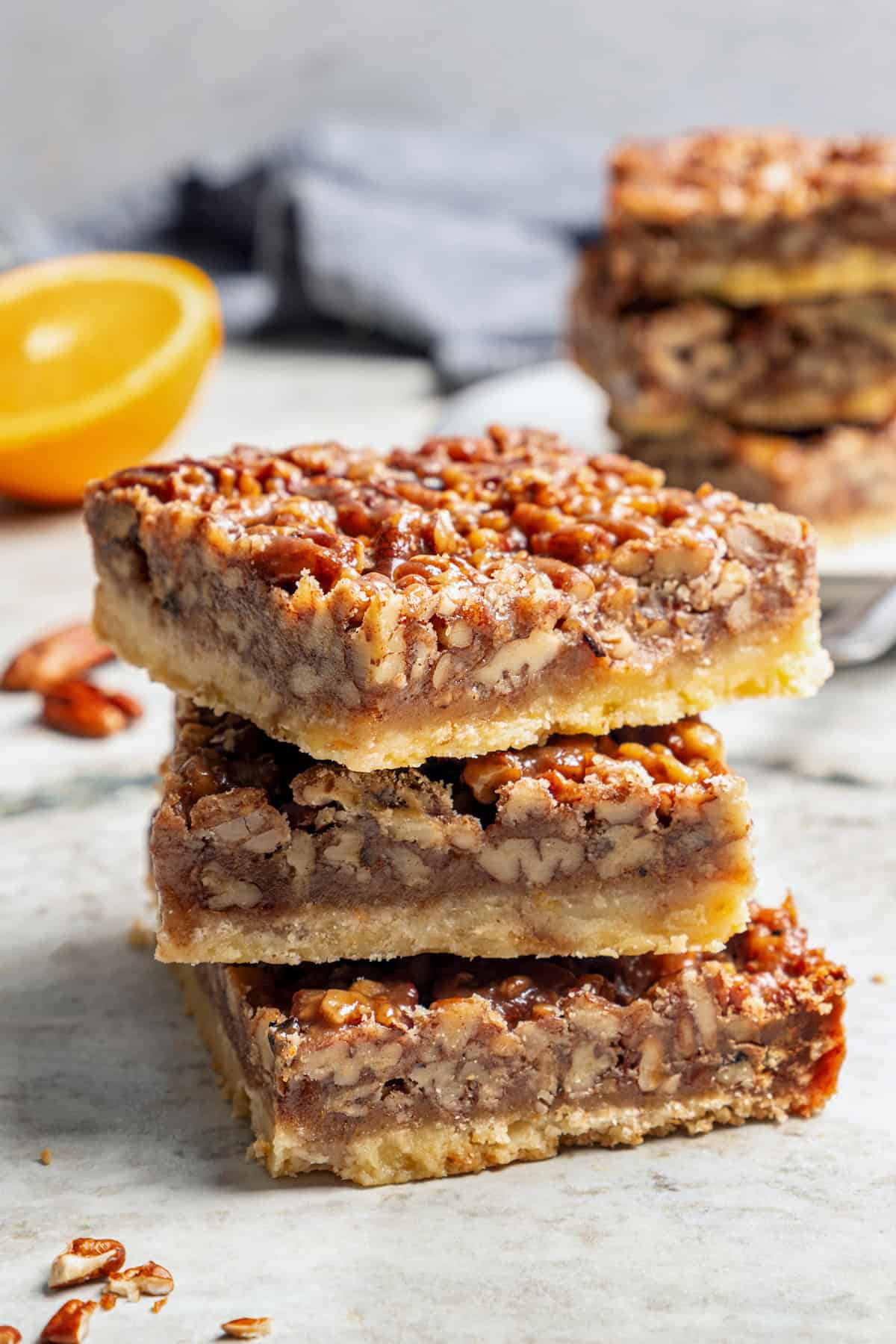 These Pecan Pie Bars have a caramel filling, buttery shortbread crust and NO corn syrup! Honey and brown sugar adds the perfect sweetness. a stack of pecan pie bars