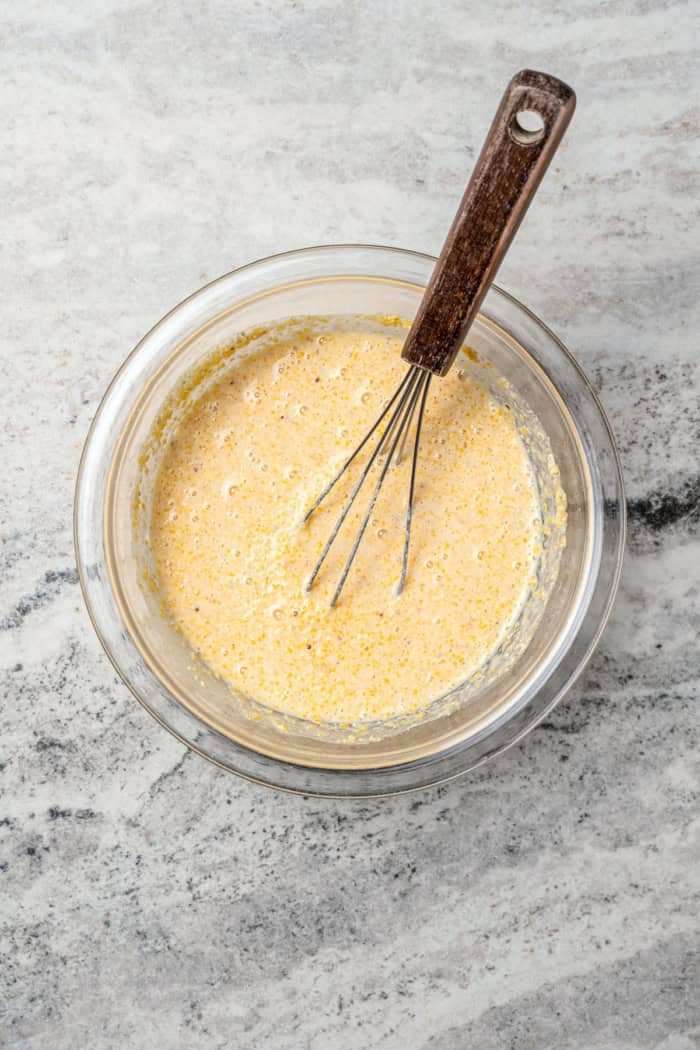This Southern Spoon Bread recipe is fluffy, soft and lightly sweet, like a cross between cornbread and soufflé. A perfect holiday side dish! Whisking cornmeal mixture in bowl.