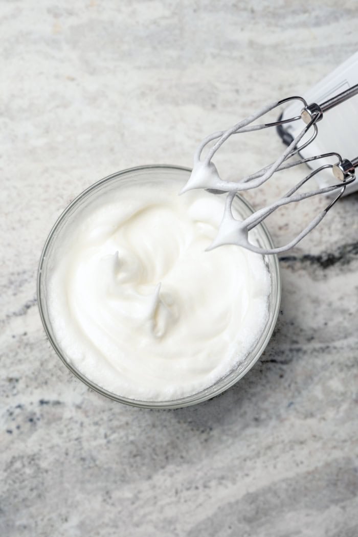Whipped egg whites in bowl with beaters.