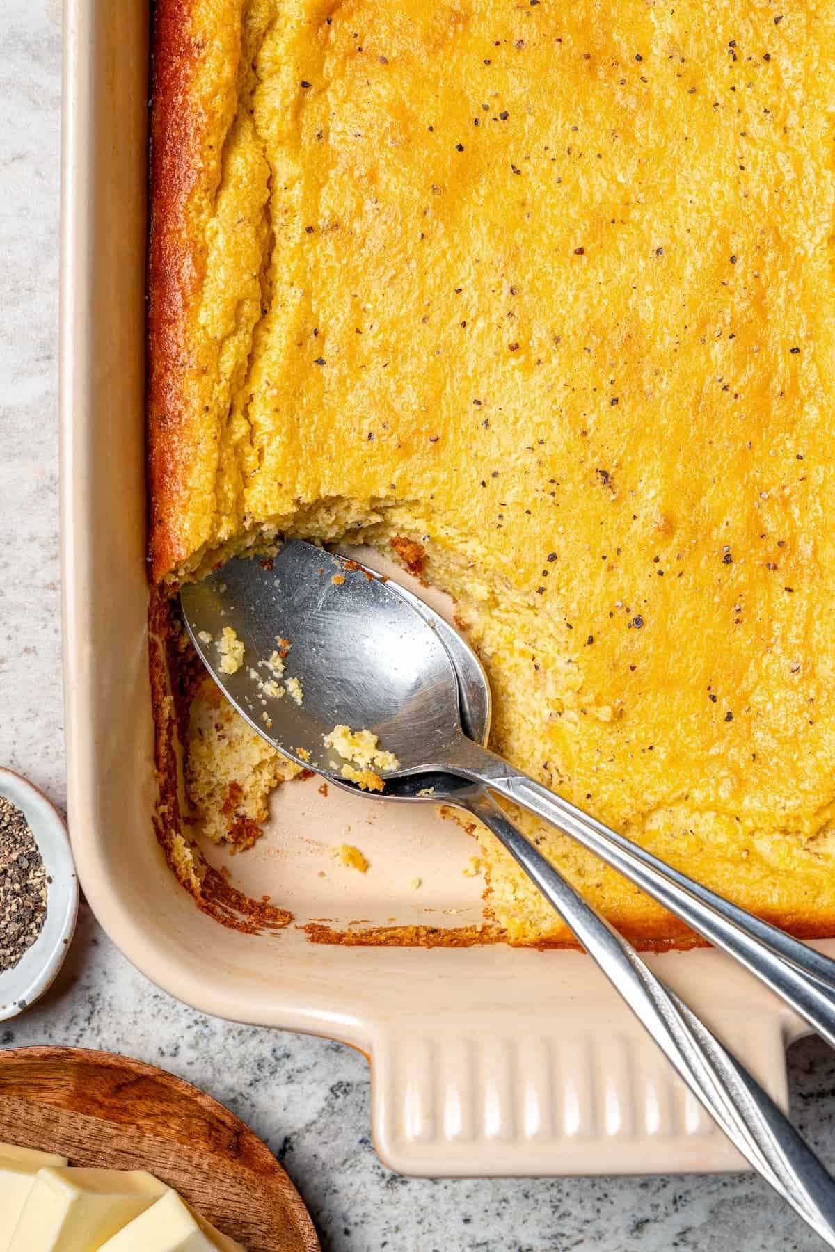 This Southern Spoon Bread recipe is fluffy, soft and lightly sweet, like a cross between cornbread and soufflé. A perfect holiday side dish! Spoon bread in casserole dish with two spoons.