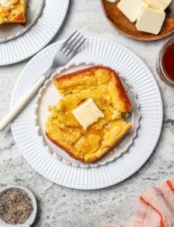 Spoon bread on plate with honey and butter.