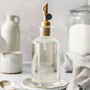 a clear bottle with a gold pour spout on top, full of simple syrup