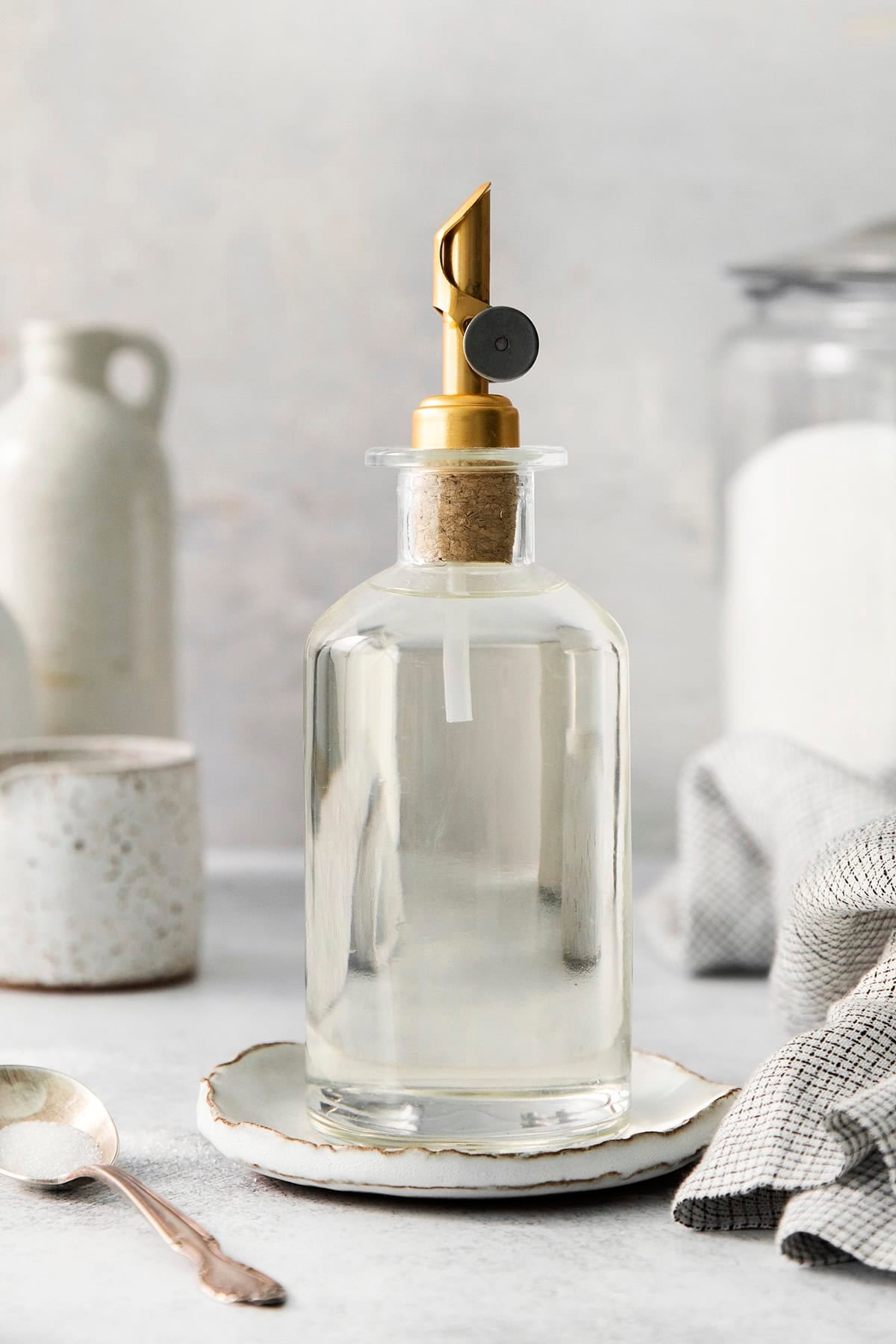a clear bottle with a gold pour spout that has simple syrup in it