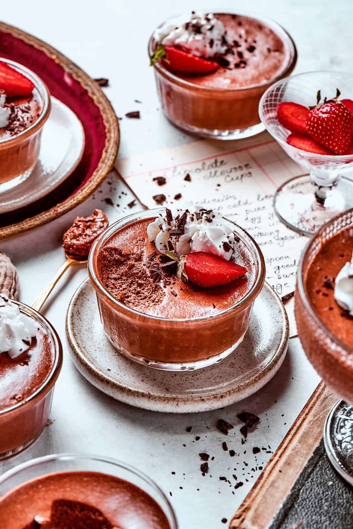 These decadent and delicious Chocolate Mousse Cups are the perfect personal-sized dessert! Serve them at a party and they’ll disappear FAST. several cups of chocolate mousse with whipped cream and strawberries