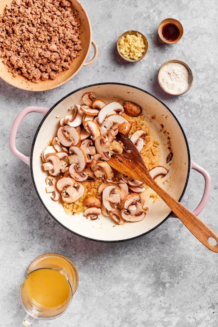 This creamy Ground Beef Stroganoff recipe is made from scratch without canned soup! An easy, budget-friendly dinner your family will love. Sliced cremini mushrooms added to skillet.