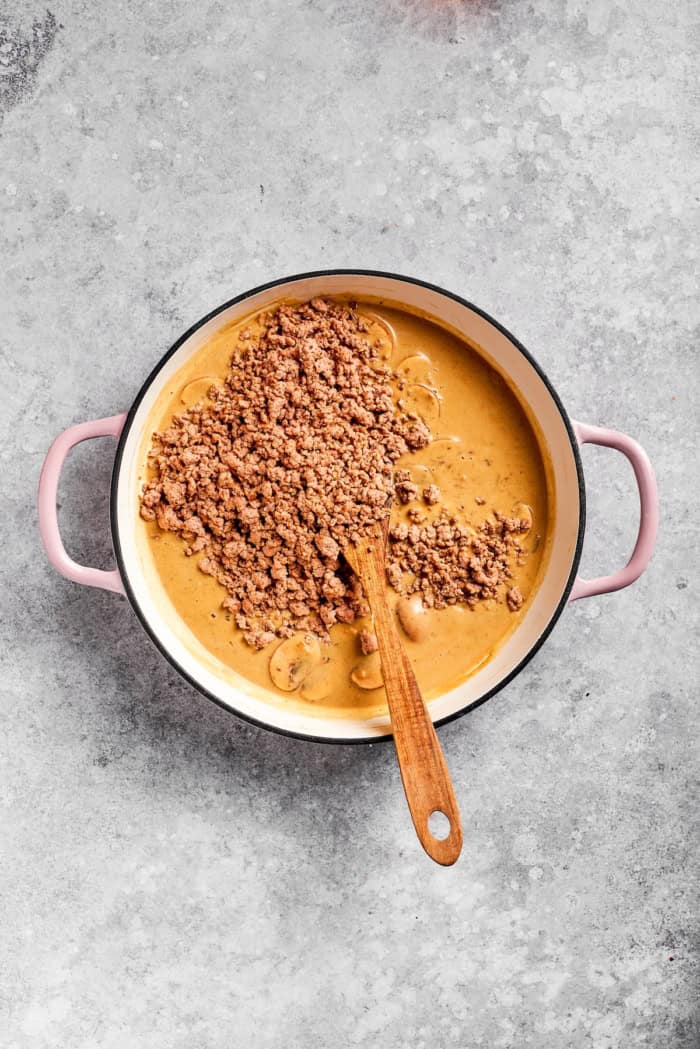 This creamy Ground Beef Stroganoff recipe is made from scratch without canned soup! An easy, budget-friendly dinner your family will love. Ground beef added to pan of stroganoff sauce.