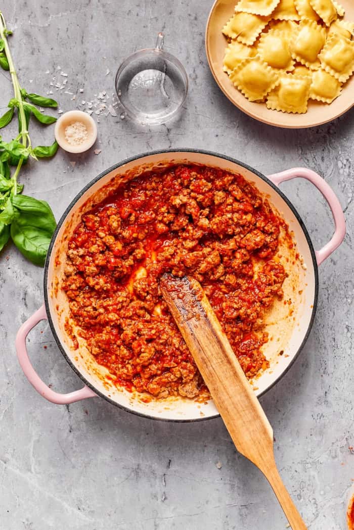 With a hearty meat sauce and plenty of cheese, this Lazy Ravioli Lasagna recipe delivers the flavor of the classic without the fuss! Meat sauce in cast iron pan.