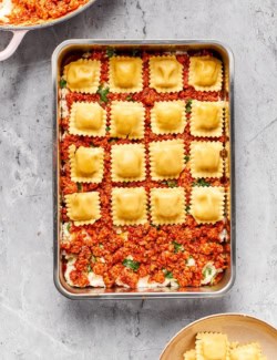 Layer of ravioli being added to lasagna pan.