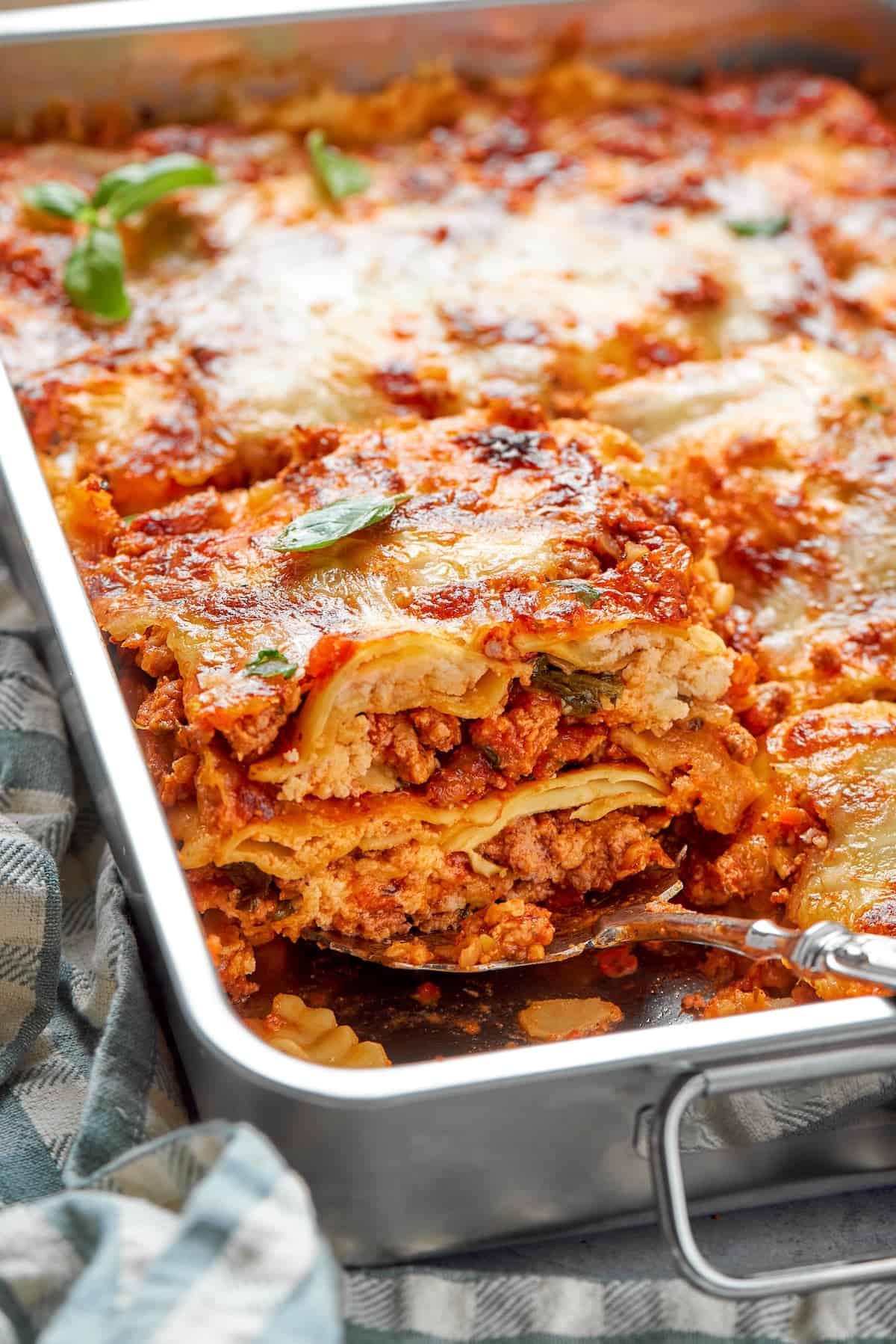 With a hearty meat sauce and plenty of cheese, this Lazy Ravioli Lasagna recipe delivers the flavor of the classic without the fuss! Serving spoon lifting portion of ravioli lasagna from pan.