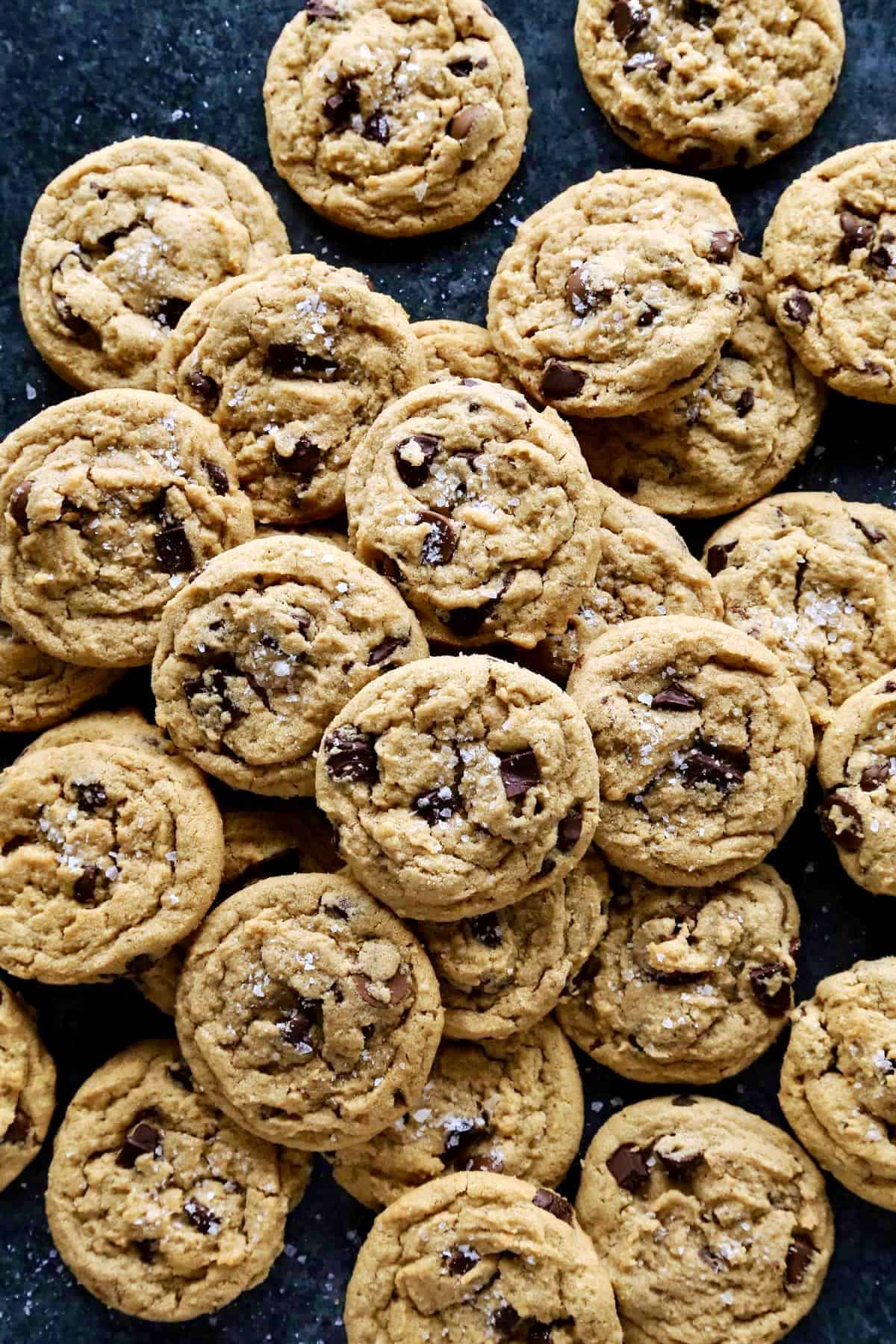 These soft, chewy peanut butter chocolate chip cookies are extra wonderful with three kinds of chocolate, plus a sprinkle of sea salt! overhead photo of a big spread of peanut butter chocolate chip cookies