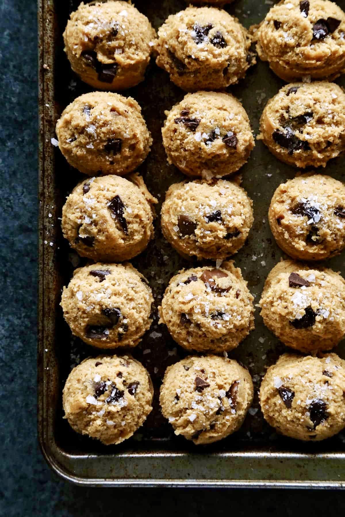overhead photo of scoops of peanut butter chocolate chip cookie dough on a rimmed sheet pan