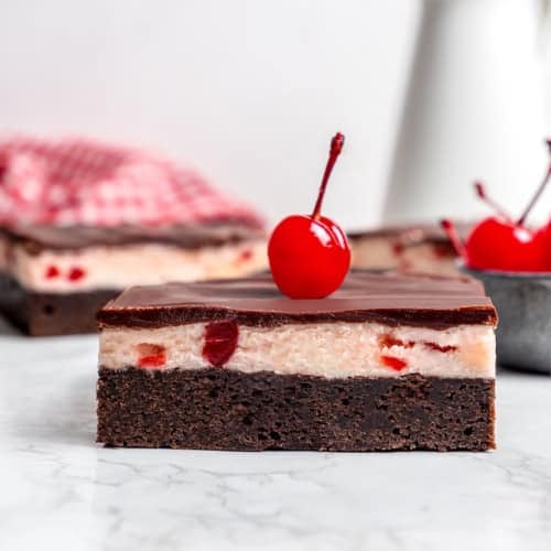 side view of a cherry chocolate brownie with a maraschino cherry on top