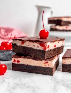side view of a stack of cherry chocolate brownies with a maraschino cherry on top