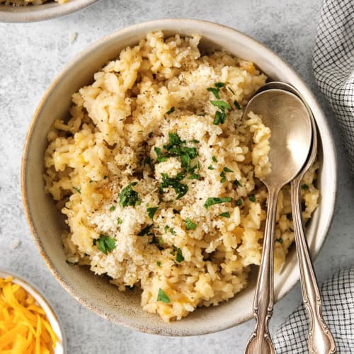 Bowl of cheesy rice with two spoons.
