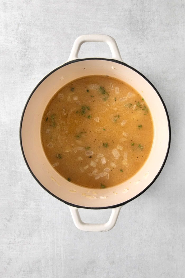 Chicken broth added to pot of rice and aromatics.