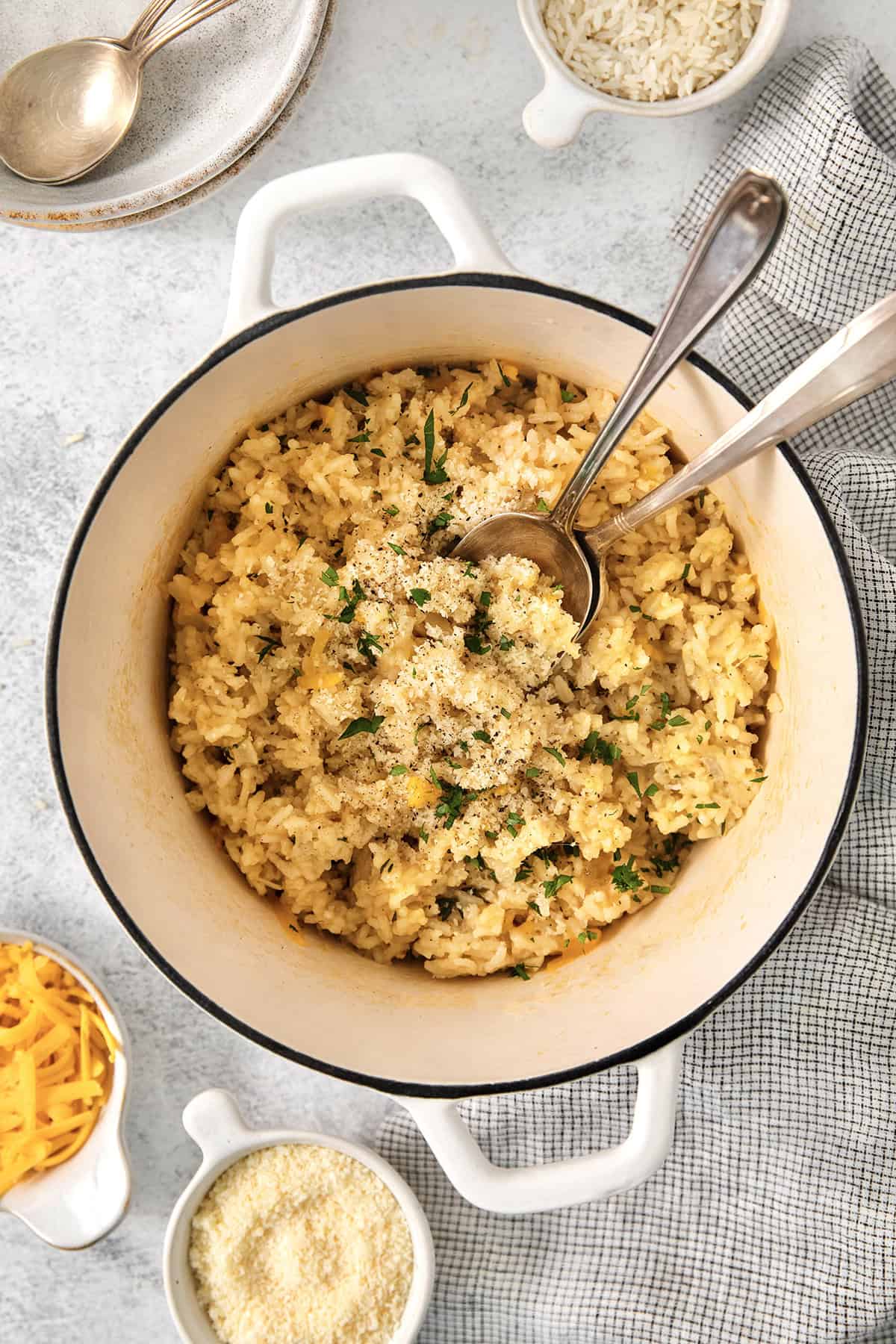 Pot of cheesy rice set next to small bowls of cheddar and Parmesan.