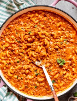 overhead photo of a pink pot of cheesy hamburger helper, with a spoon in it
