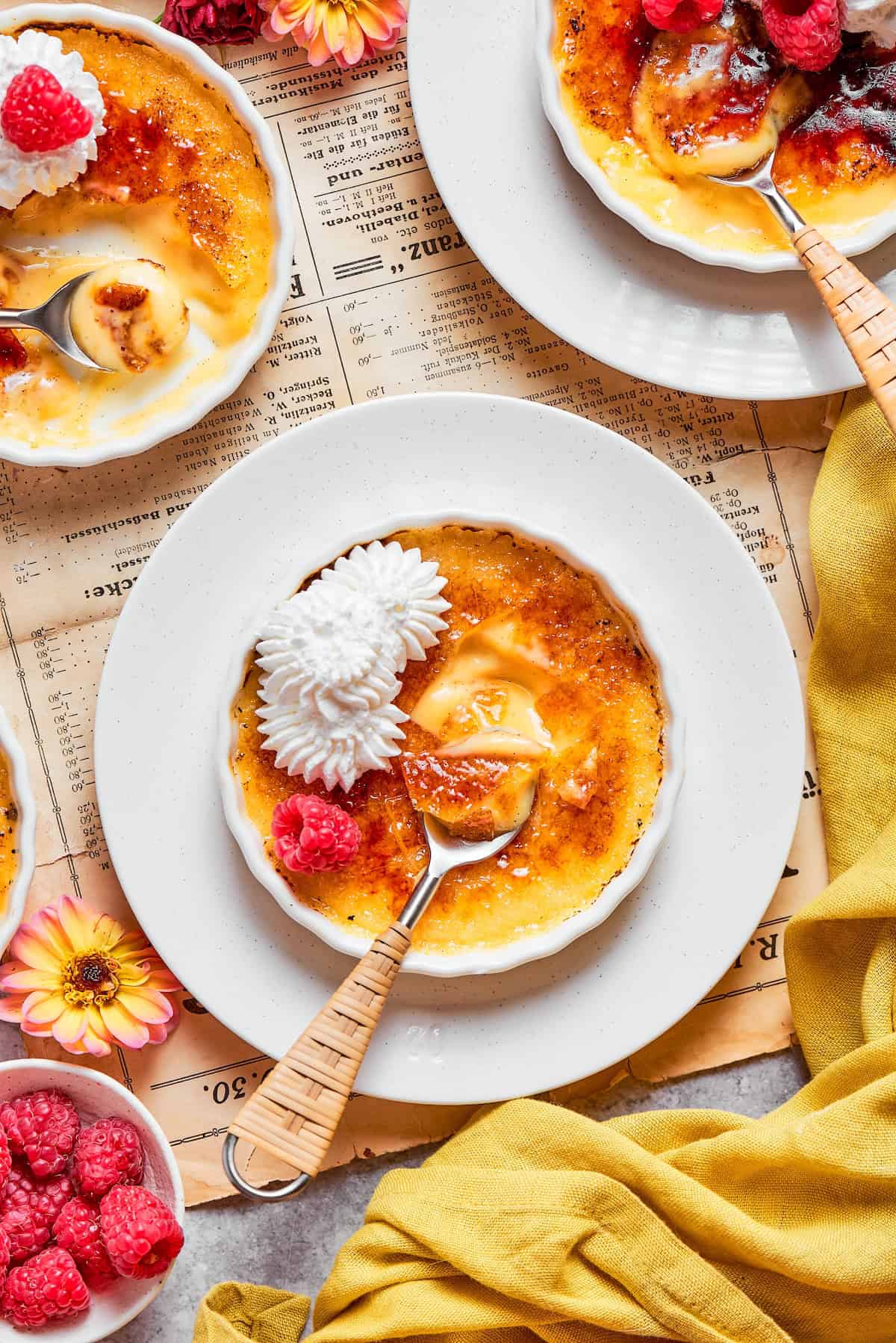 The silky custard in this Almond Vanilla Crème Brûlée lies beneath a glorious caramelized top. An elegant dessert that's surprisingly easy! overhead photo of white ramekins with creme brulee