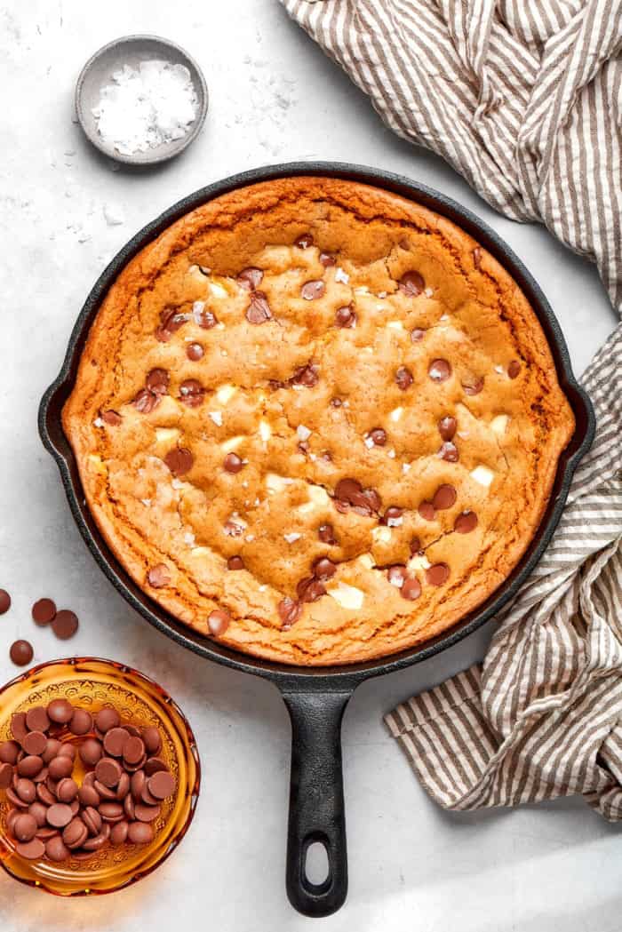 Nutty brown butter, flaky sea salt and fluffy buttercream make this chewy chocolate chip skillet cookie worthy of a celebration. So easy too! overhead photo of baked chocolate chip skillet cookie